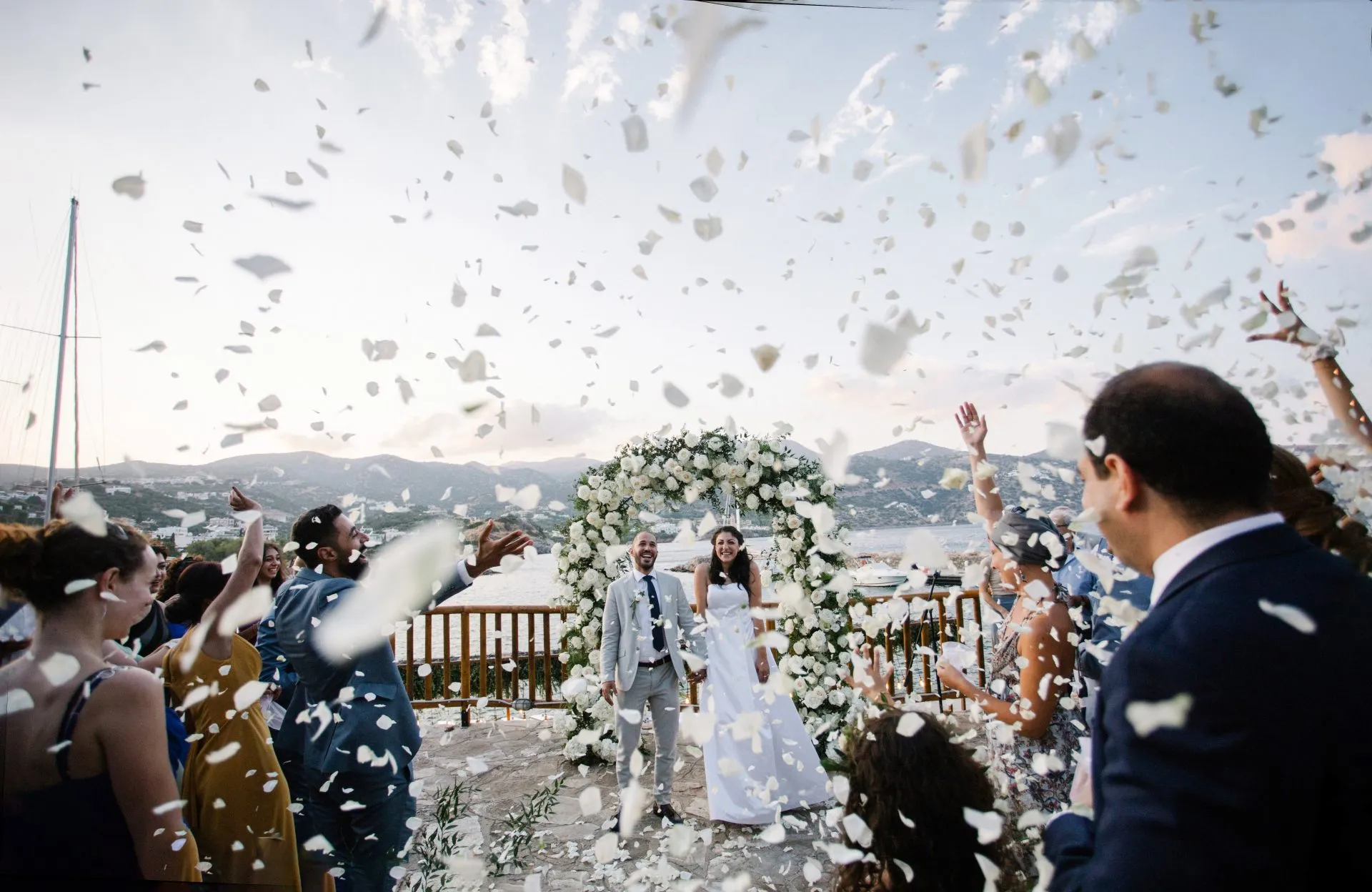 Petals fill the air as newlyweds walk out of their seaside wedding ceremony in Crete